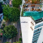 A striking aerial view of the Andaz Mexico City hotel, showcasing its rooftop pool, modern architecture, and the tree-lined streets of the vibrant Condesa neighborhood.
