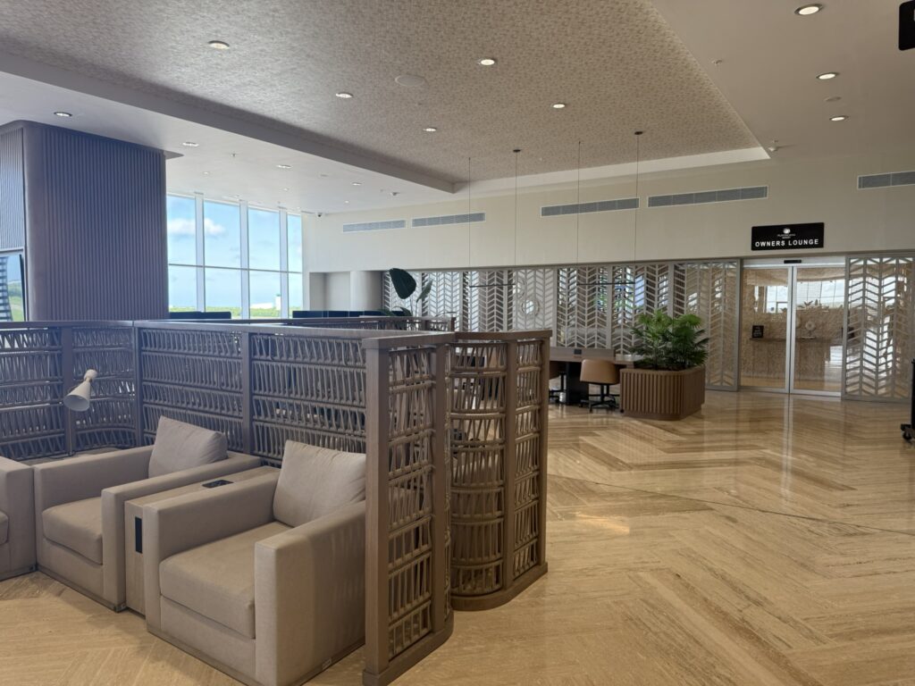 Private seating area near the Owners Lounge inside the Punta Cana VIP Lounge, with cushioned armchairs, partitioned sections, and runway views through floor-to-ceiling windows.