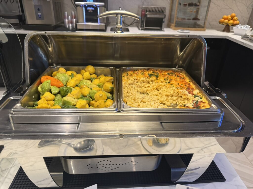 Hot buffet dishes in the Regency Club at Hyatt Regency JFK, featuring sautéed squash and baked macaroni and cheese.