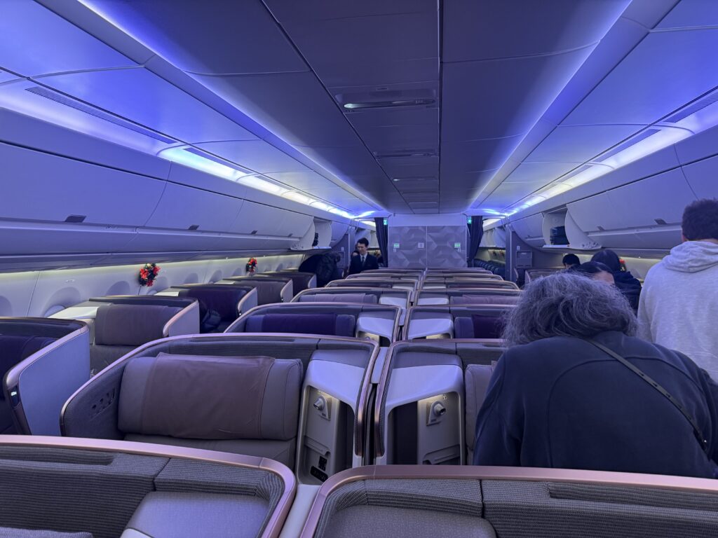 Singapore Airlines A350 Business Class cabin showing spacious 1-2-1 seating layout with purple accent lighting during boarding.
