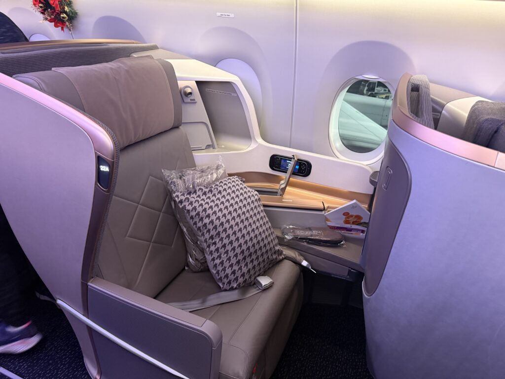  Singapore Airlines Business Class seat on the A350 with wide lie-flat pod, large side console, and window view on the JFK to Singapore flight.