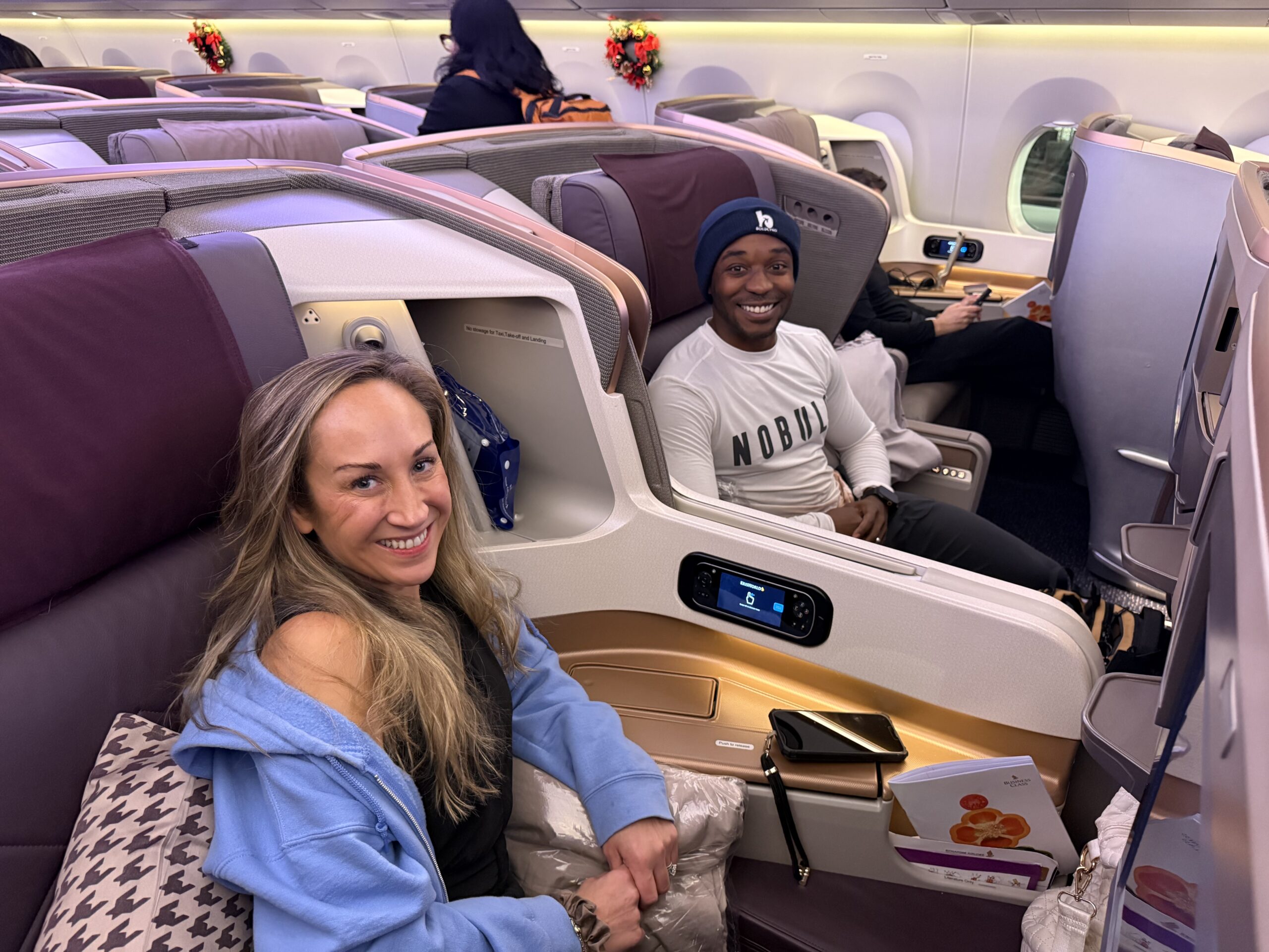 Couple seated in Singapore Airlines Business Class middle seats on the A350, showing spacious pods ideal for couples traveling together.
