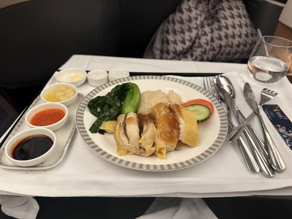 chicken rice with fragrant rice, sliced chicken, greens, and traditional sauces