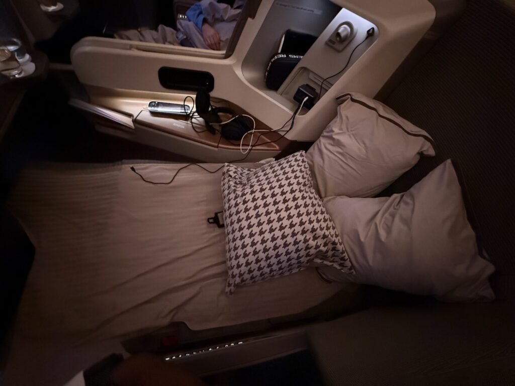 Singapore Airlines Business Class lie-flat bed setup with full-length mattress, pillows, and personal storage on Airbus A350.