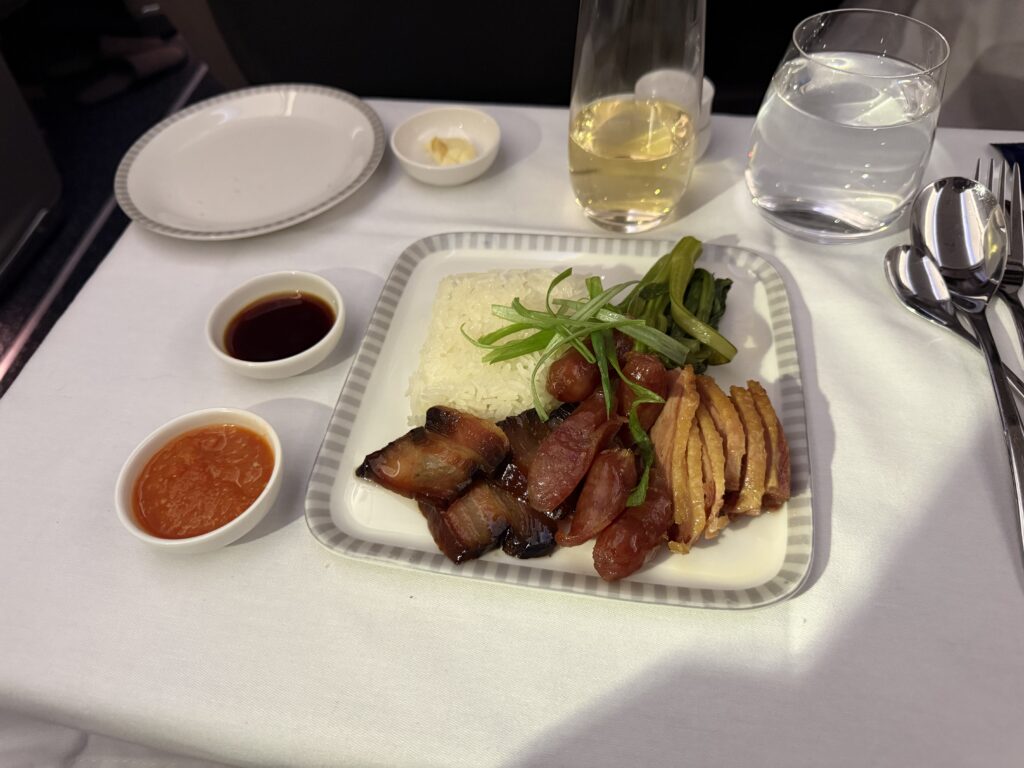 Singapore Airlines Business Class Cantonese rice main course with steamed rice, vegetables, sliced Pork, and multiple sauces.