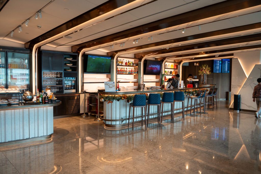 Main bar area inside the Singapore Airlines SilverKris Lounge at Changi Airport with high-top seating and bartenders.