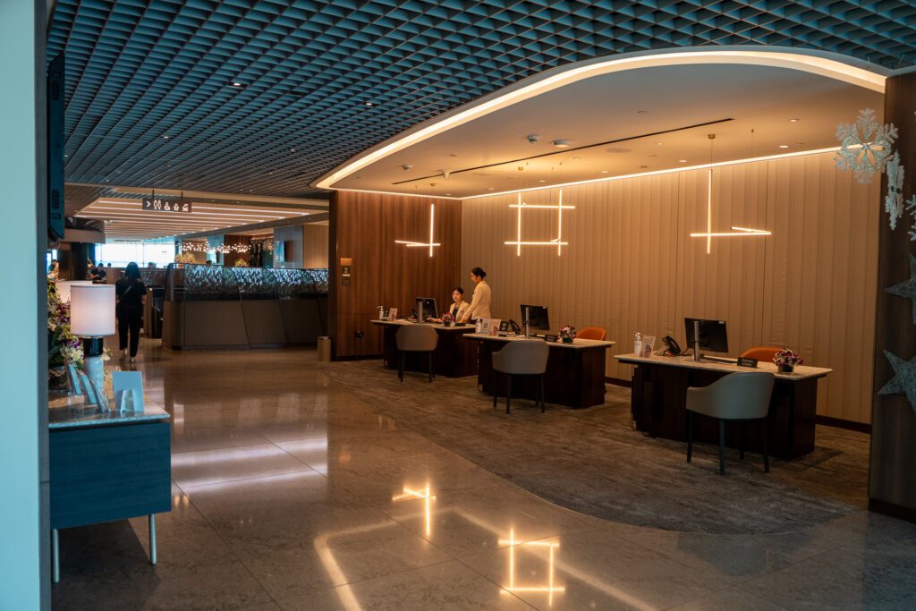 Reception desk inside the Singapore Airlines SilverKris Lounge at Changi Airport with staff assisting guests.