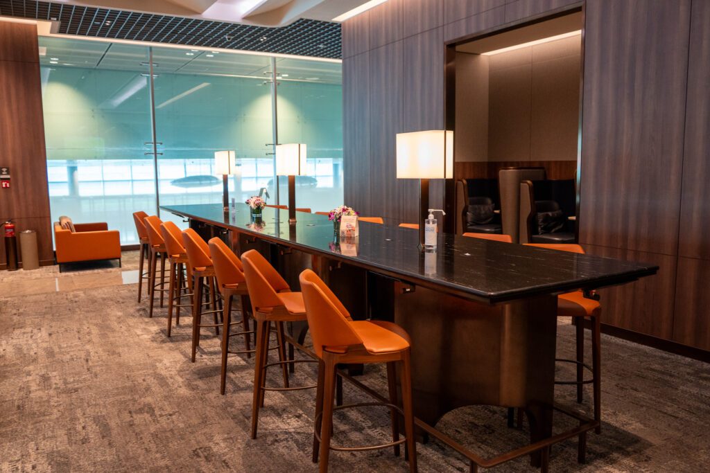 Communal high-top table with bar seating inside the Singapore Airlines SilverKris Lounge at Changi Airport.