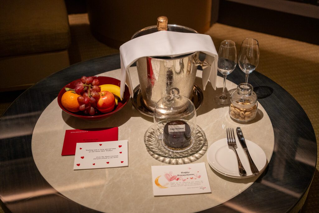 Welcome champagne, fruit, and honeymoon amenity arranged on a table in a Grand Hyatt Hong Kong suite