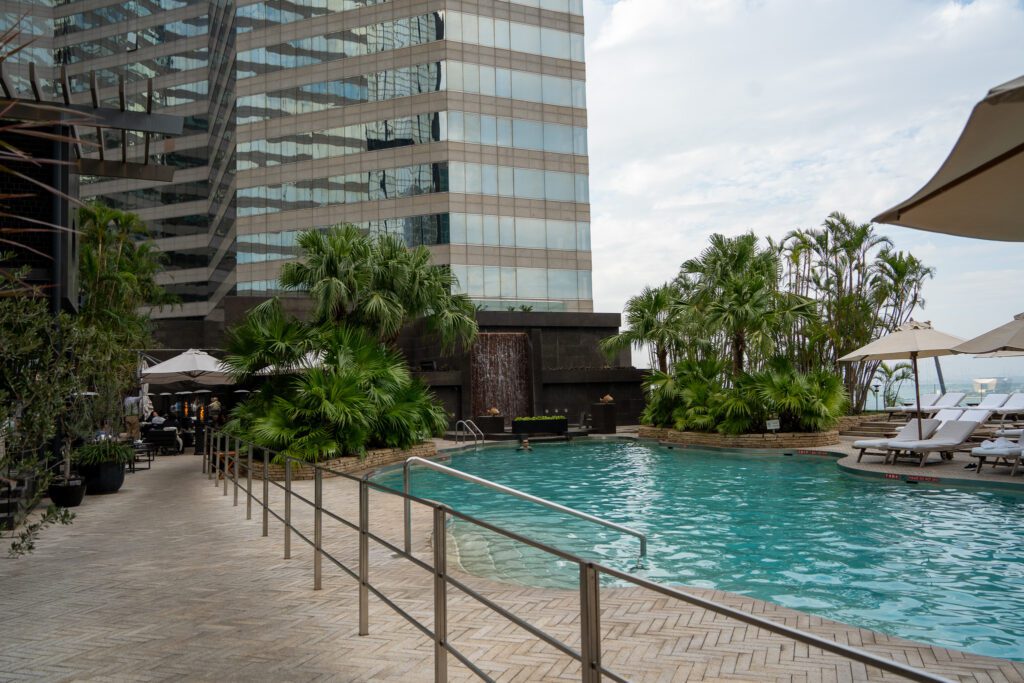 Outdoor swimming pool at the Grand Hyatt Hong Kong surrounded by palm trees and lounge chairs