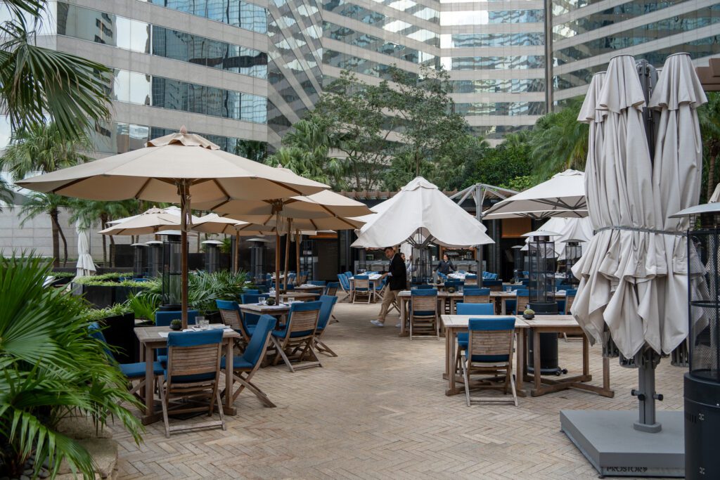 Outdoor restaurant terrace at the Grand Hyatt Hong Kong with umbrella seating surrounded by greenery in Wan Chai