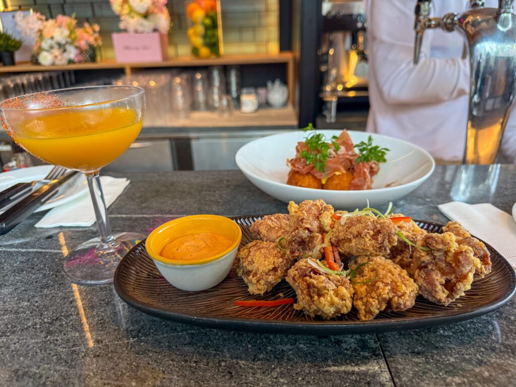 Poolside food and cocktails at the Grand Hyatt Hong Kong, featuring fried chicken, dipping sauce, and a cocktail served near the hotel pool bar