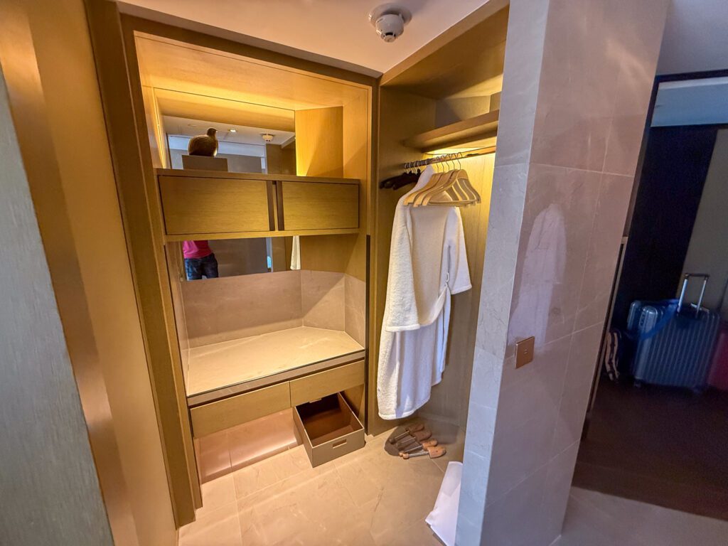 Walk-in closet area with plush hotel robes inside a Victoria Harbour Executive Suite at the Grand Hyatt Hong Kong