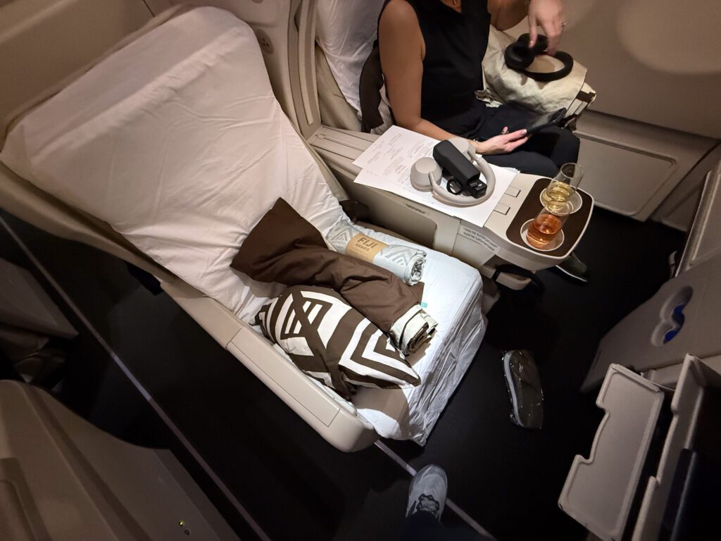 Fiji Airways A330 business class seat in angled-flat position with pillow and high-quality blanket on the Hong Kong to Nadi flight.
