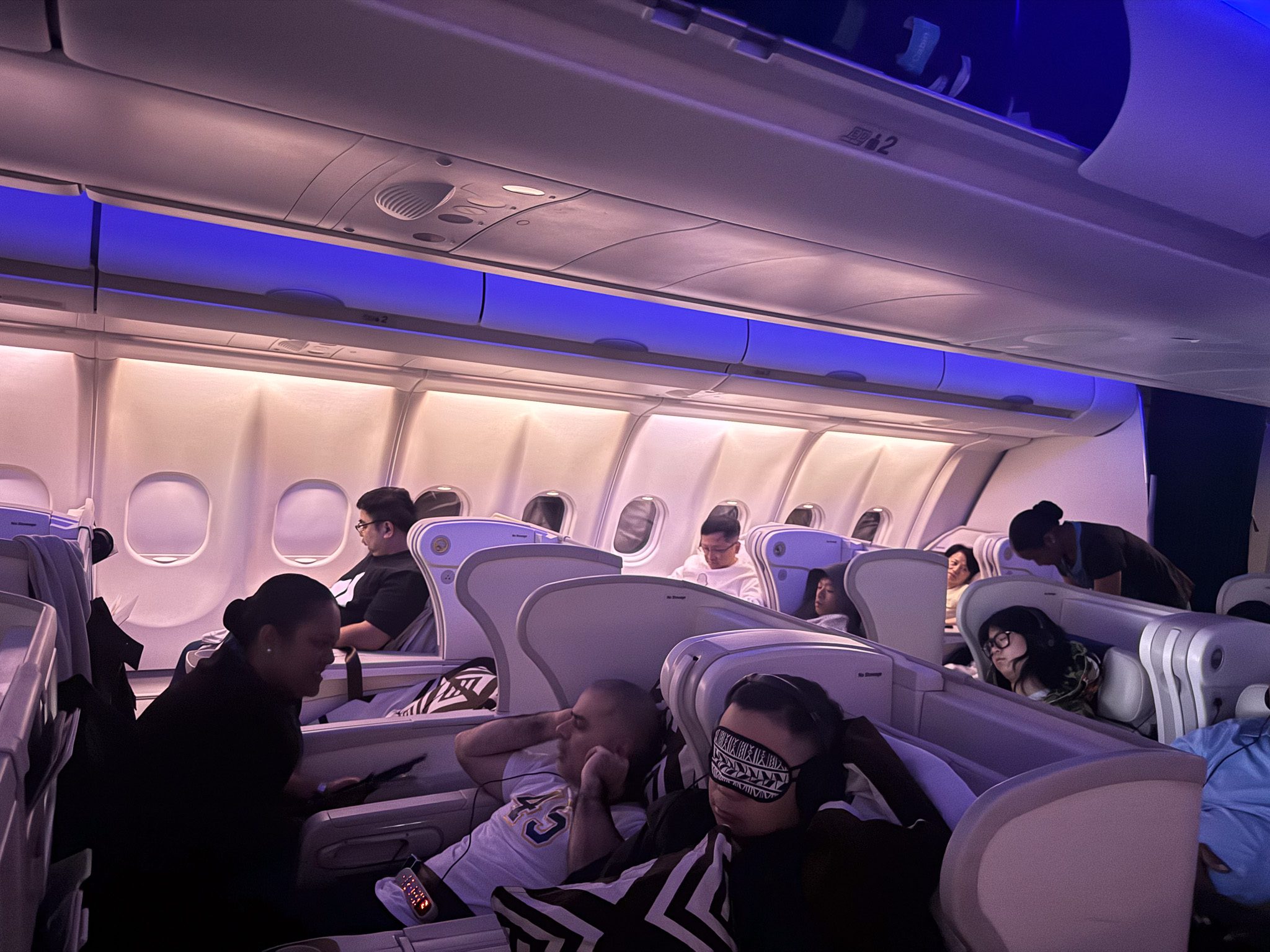 Fiji Airways A330 business class cabin at night with 2-2-2 seat configuration and passengers resting during the Hong Kong to Nadi flight.