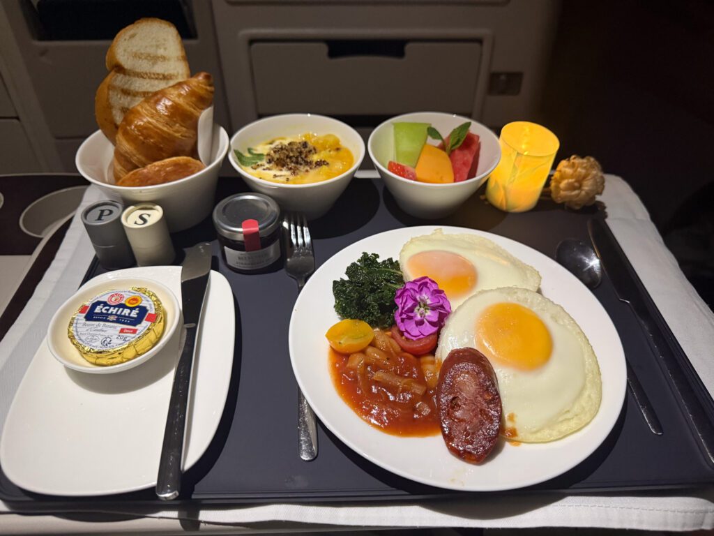 Fiji Airways A330 business class breakfast featuring baked eggs, chorizo, kale, white bean ragu, pastries, fruit, and yogurt.