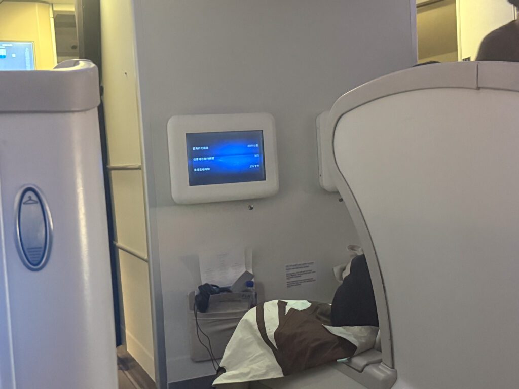 Fiji Airways A330 business class bulkhead seat with angled-flat bed setup and cabin wall flight information display on the Hong Kong to Nadi route.