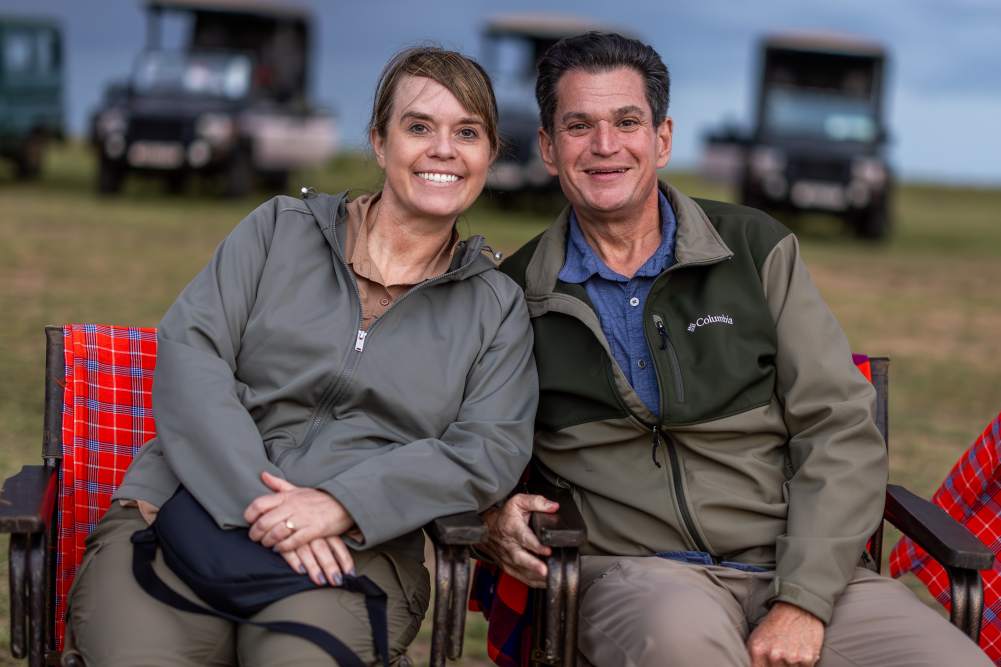 Couple seated outdoors at sunset during a luxury safari stay at JW Marriott Masai Mara Lodge.