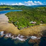 Drone aerial view of Namale Resort & Spa on a lush private peninsula in Fiji surrounded by turquoise ocean and coral reef.