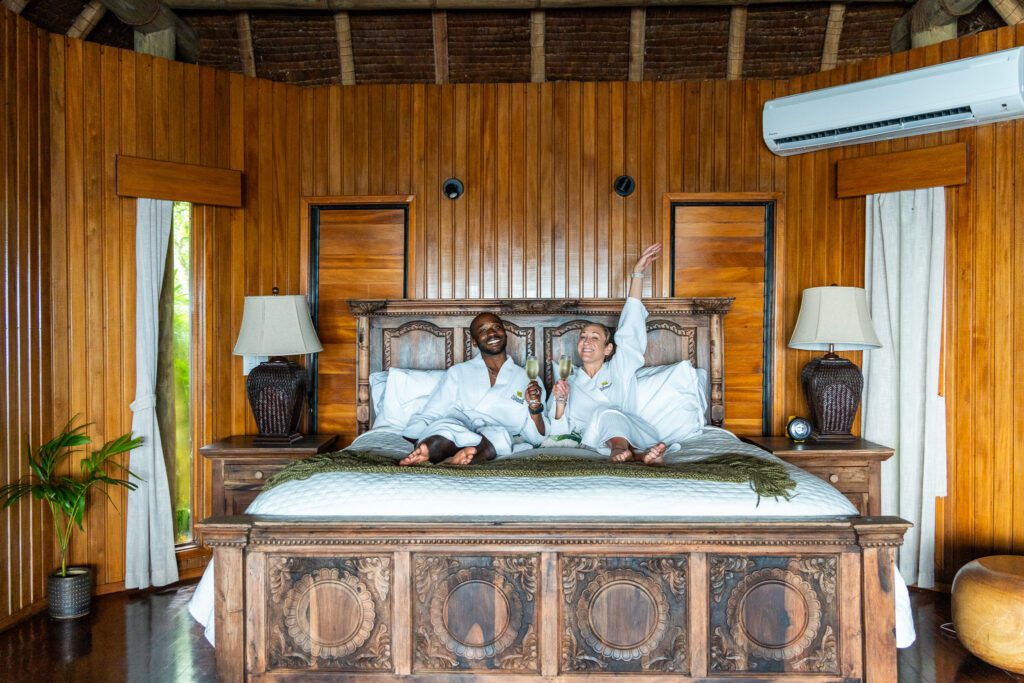 Couple relaxing with champagne in a private luxury villa bedroom at Namale Resort & Spa in Fiji.
