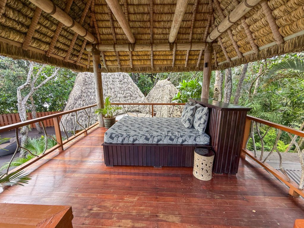 Covered wooden balcony with cushioned daybed overlooking tropical foliage at Namale Resort & Spa.
