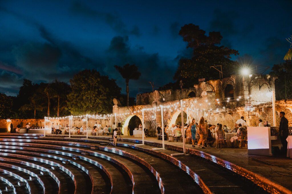 Guests seated for an evening wedding reception under string lights at the Altos de Chavón amphitheater at Casa de Campo in the Dominican Republic.