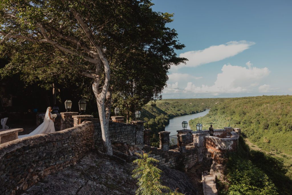 Bride standing on the stone overlook at Altos de Chavón at Casa de Campo, with sweeping views of the Chavón River and lush Dominican Republic landscape.