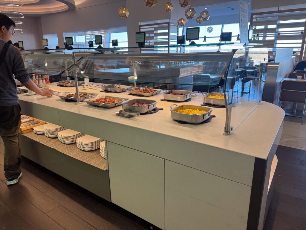 American Airlines Flagship Lounge buffet with hot food options and seating area