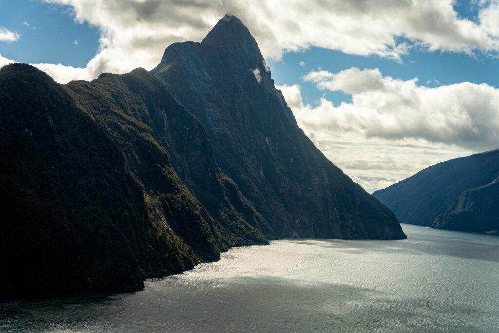 Mitre Peak rising above Milford Sound with sunlight reflecting on the fjord water