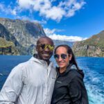 Couple smiling on Milford Sound cruise boat with mountains and fjord behind them