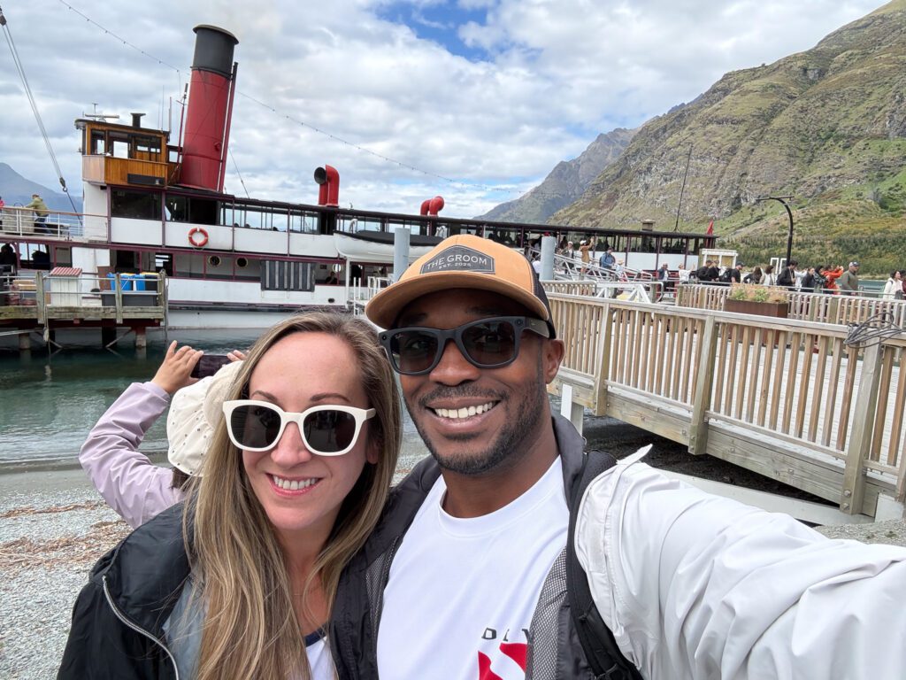 Couple in front of the TSS Earnslaw steamship in Queenstown before the Walter Peak Farm Tour