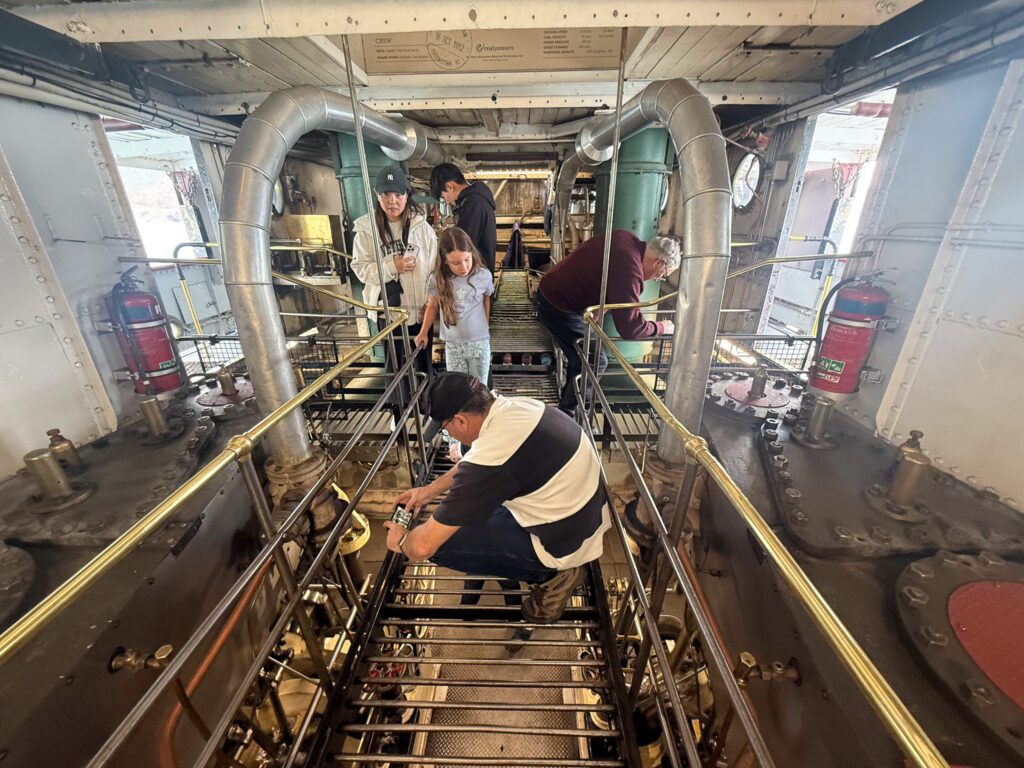 Passengers viewing the working steam engine inside the TSS Earnslaw engine room