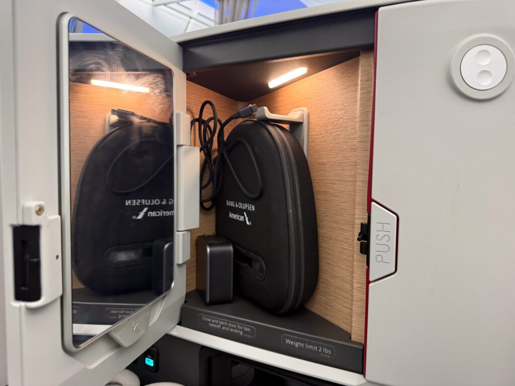 American Airlines business class storage compartment with Bang & Olufsen headphones