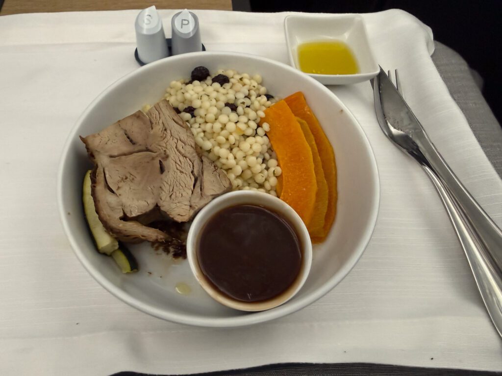 American Airlines business class main course with sliced meat, couscous, and vegetables on 787-9
