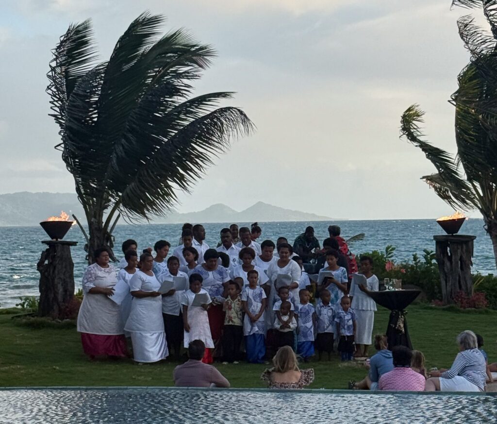 Traditional Fijian choir performance at sunset ceremony overlooking the beach at Nanuku Resort Fiji