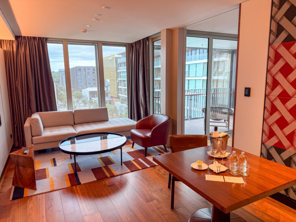 Park Suite living room at Park Hyatt Auckland featuring floor-to-ceiling windows, dining table, lounge seating, and private balcony access
